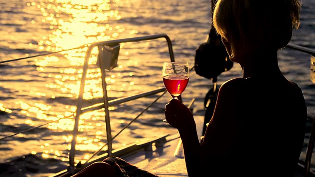 在夕阳下航行时喝葡萄酒的女士视频素材