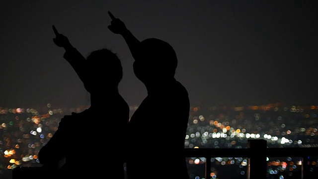 年轻情侣在城市的夜晚观看星星，4k(超高清)视频下载
