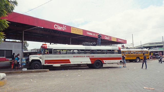 里瓦斯尼加拉瓜汽车站正在拍摄/放映。一名男子站在巴士车顶上，正在紧固背包和行李箱。当地人、游客和游客穿过这个中美洲小镇的街道。视频素材