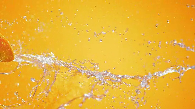 一半的橙色被水射流击中在橙色的背景视频下载