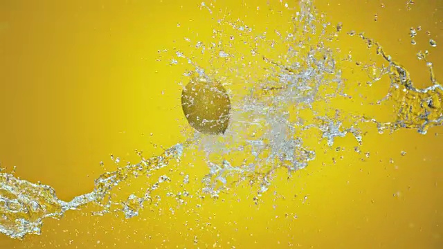 SLO MO柠檬被水喷在黄色背景上视频下载