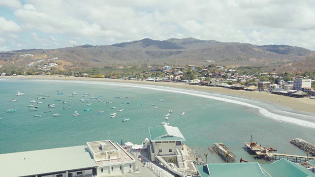 从圣胡安德尔苏尔海滩的有利位置。建立拍摄/ b-roll。我们可以看到这个尼加拉瓜中美洲小镇的海湾，太平洋碧绿的海水，休闲船和当地的渔业建筑。视频素材