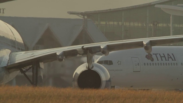 在泰国普吉岛机场，空中客车A330商用客机在日出的天空降落，并在跑道上移动到航站楼。(3段剪辑)视频下载