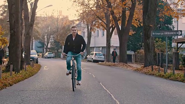 一名年轻人骑着自行车沿着树木环绕的道路行进视频素材