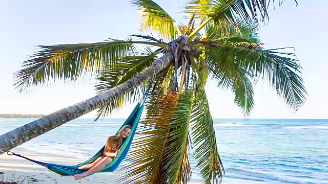 右，年轻女子躺在热带海滩的吊床上视频素材