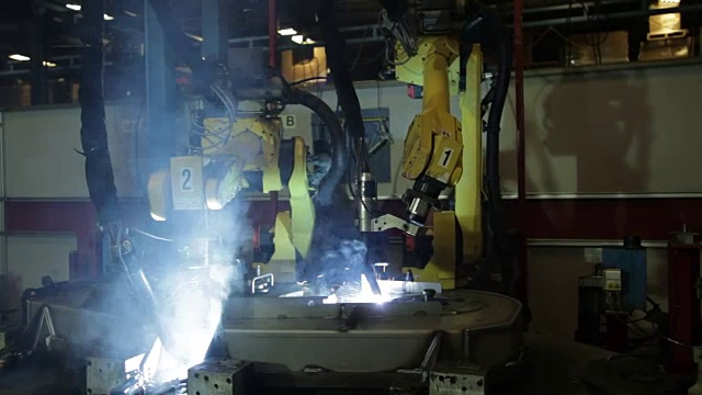 机器人手臂在美国一家制造工厂焊接钢铁部件，产生火花和烟雾。视频素材