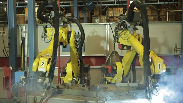 美国一家工厂的广角双机器人焊工。视频素材