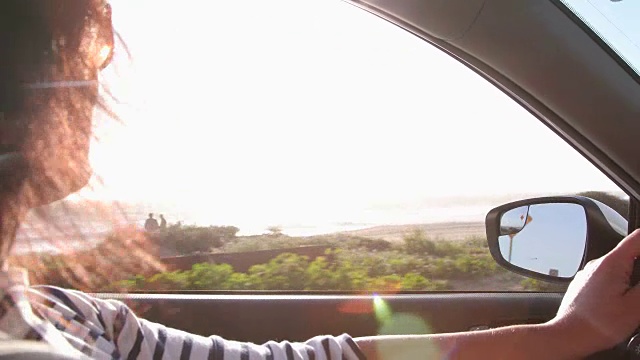 女人开着车，享受着从敞开的窗户吹进来的微风。视频素材