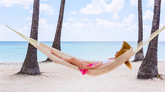 铜潘走后，年轻女子躺在热带海滩的吊床上视频素材