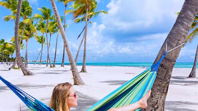 MS追踪着，一个年轻的女人躺在热带海滩的吊床上视频素材