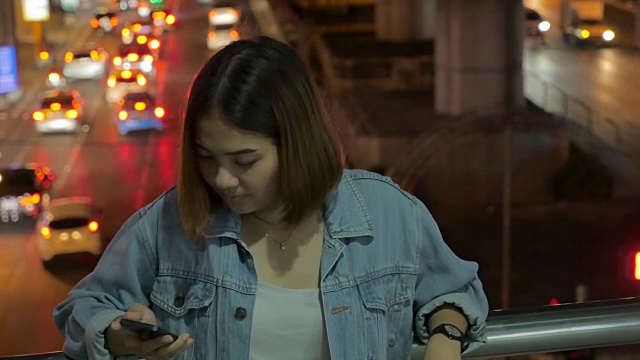 年轻女子使用智能手机与美丽的散景，特写平移视频素材