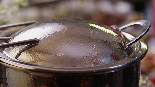 近距离的一个热气腾腾的铁锅充满了肉丸，盘排骨和水果在宴会桌上。视频下载