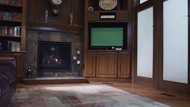 家庭房间书房配有一个燃烧的壁炉和绿色屏幕电视。视频下载