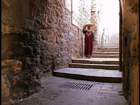 穆斯林妇女头上提着篮子走下小巷的楼梯/耶路撒冷老城视频下载