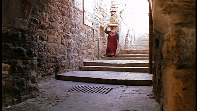 慢镜头穆斯林妇女头上提着篮子走下小巷的楼梯/耶路撒冷老城视频下载