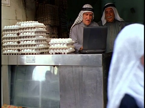 两名高级阿拉伯鸡蛋小贩在户外市场/耶路撒冷的摊位上使用笔记本电脑视频下载