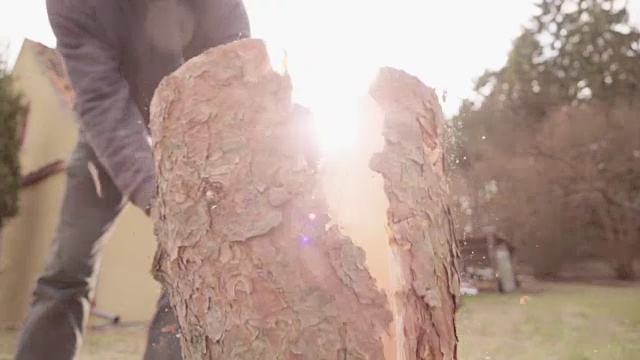 慢镜头:用斧头劈柴，背景是阳光视频素材
