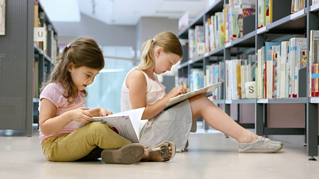 两个女孩坐在公共图书馆的地板上看书视频素材