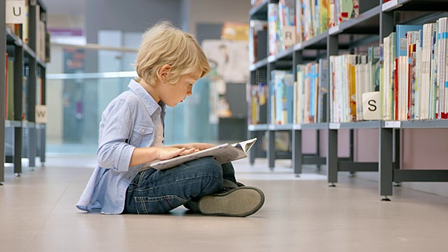DS小男孩坐在图书馆里看书视频素材