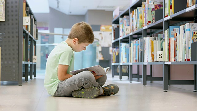 DS男孩坐在图书馆的过道上看书视频素材