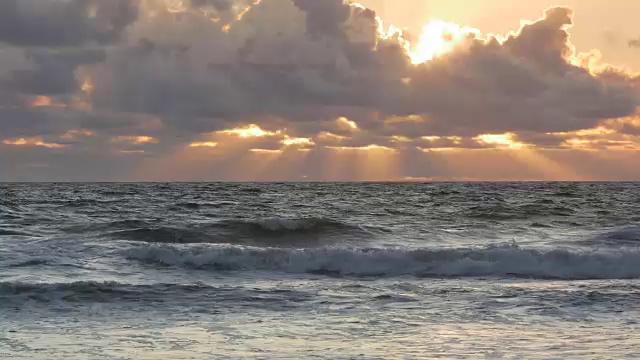 银色的海洋，地平线上戏剧性的云和橙色的阳光，海豹游泳视频下载