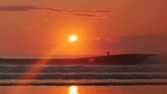 站着划桨的人，海浪在海洋上，橙色的太阳升起的剪影视频下载
