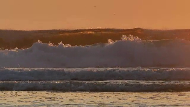 大的，背光的海浪从低角度，银色的海洋，橙色的天空视频下载