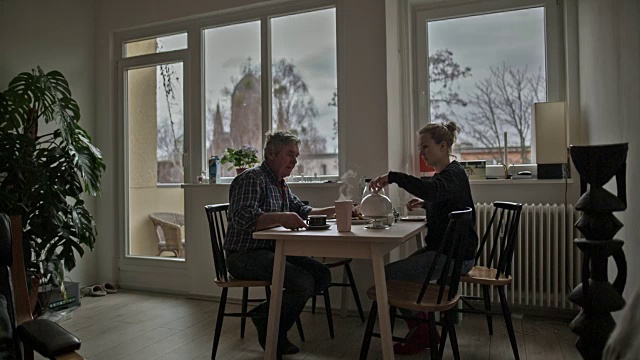 一个活跃的老人和他迷人的年轻女儿在五点钟的下午茶视频素材