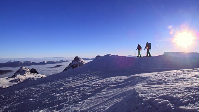穿着雪鞋在阳光下走在山顶上视频素材