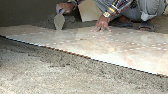 4k，建筑工人用油灰刀铺瓷砖地板视频下载