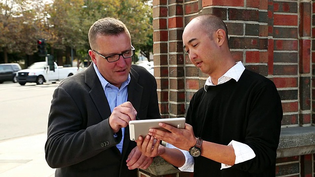 美国加州圣克鲁斯，两名男子站在平板电脑上握手签署电子签名视频素材