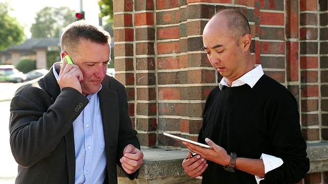 美国加州圣克鲁斯，一名手持平板电脑的男子正在用智能手机与他交谈视频素材