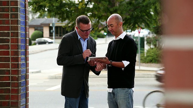 美国加州圣克鲁斯，两名男子站在写字板上签署电子签名视频素材