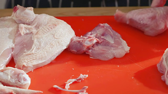 铜盘的厨师生鸡肉切成段腿和胸部红切菜板/新港,英国南威尔士aE视频素材