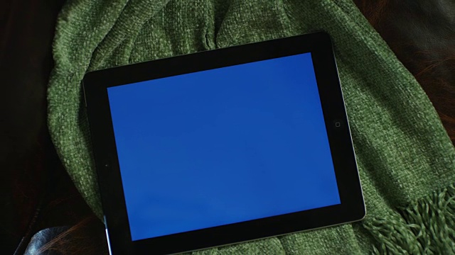 一个蓝色屏幕的笔记本电脑设置在椅子上的毯子的特写。相机变焦到广角。视频下载