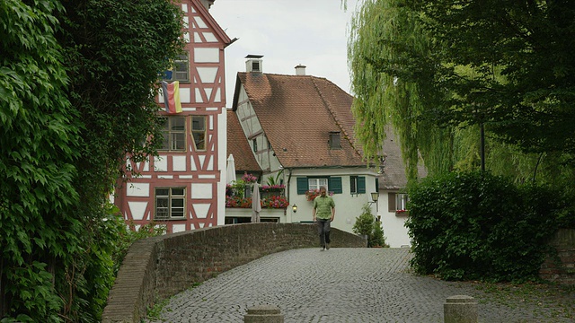 德国乌尔姆村，男子走在鹅卵石桥上的广角镜头视频素材