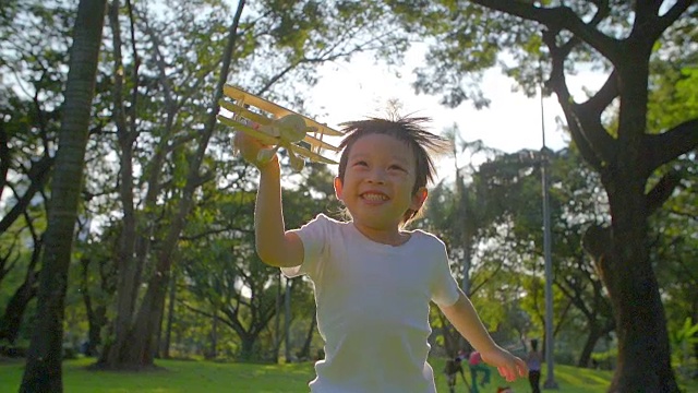 可爱的亚洲男孩在公园里玩玩具飞机视频素材