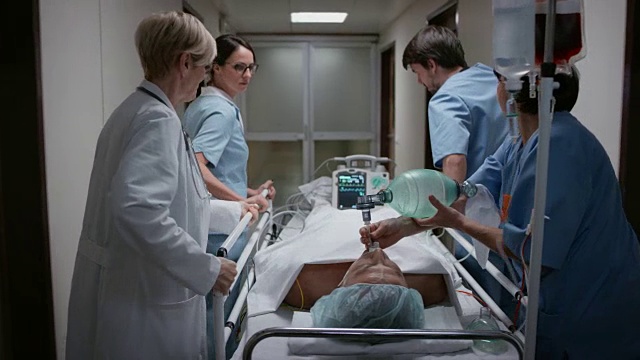 DS医生和她的医疗团队将一个病人放在轮床上转移到手术室视频素材