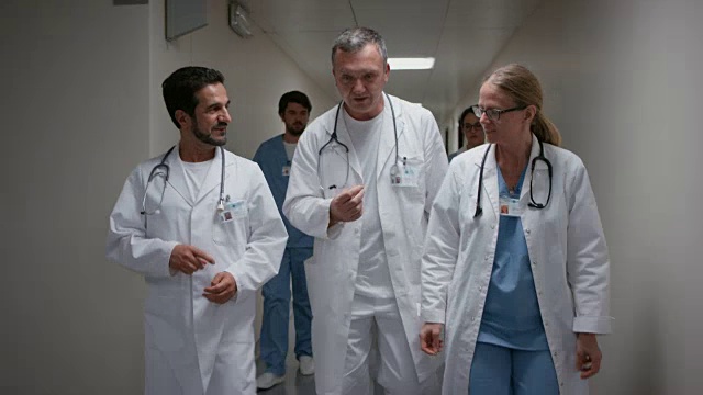 三个男医生在医院的走廊里边走边说话视频下载