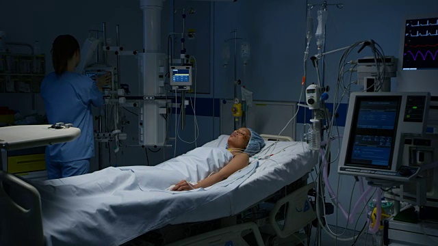 护士正在观察一位躺在重症监护室的女性病人视频下载