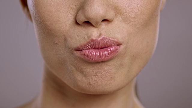 一个年轻的亚洲女人送一个吻的嘴唇视频素材