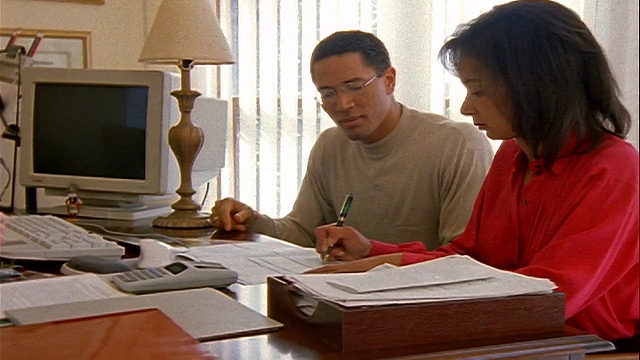 摄影用计算器拍摄财务顾问/银行家，在纸上写字+给一对黑人夫妇签名视频素材