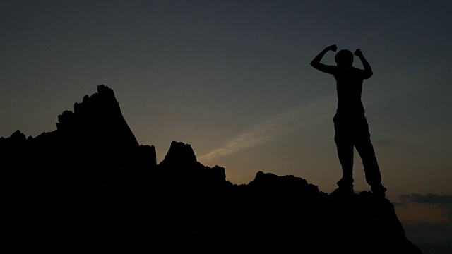 日落时岩石上一个人的剪影视频素材