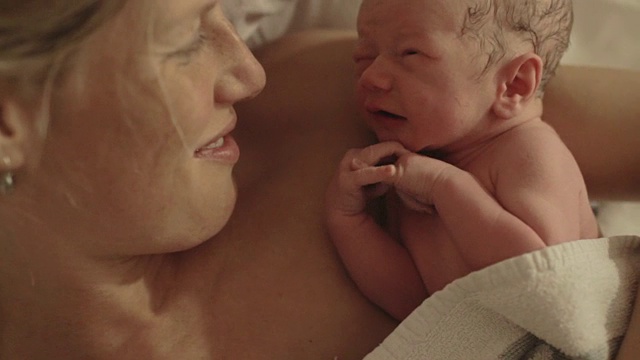抱着妈妈和新生儿，对着镜头微笑视频下载