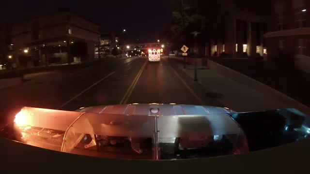从一辆救护车的顶部看第二辆救护车，在晚上沿着街道跑到城市医院，画面底部有闪烁的灯光。视频下载