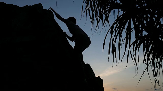 日落时岩石上一个人的剪影视频素材