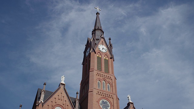 相机倾斜下和倾斜上的一个大的小镇美国基督教教堂;塔尖上装有时钟的砖结构建筑。视频下载