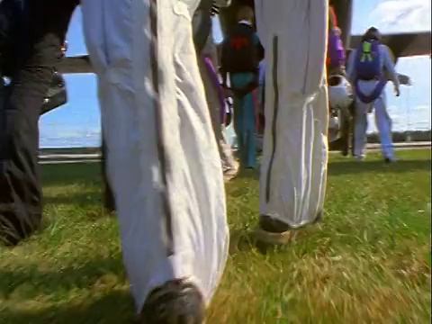 低角度后视点跳伞运动员在草地上走着五颜六色的工作服大飞机与螺旋桨视频下载