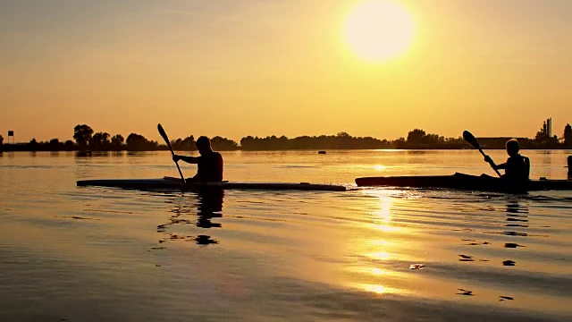 日落时孩子们在湖上划皮艇视频素材