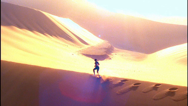 过度暴露的慢动作空中鸟瞰黑人男性运动员在沙漠的沙丘上奔跑视频下载